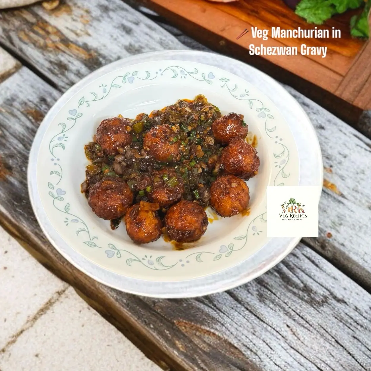 Veg Manchurian in Schezwan Gravy Veg Manchurian balls coated in spicy red Schezwan sauce served in a white bowl with herbs on top
