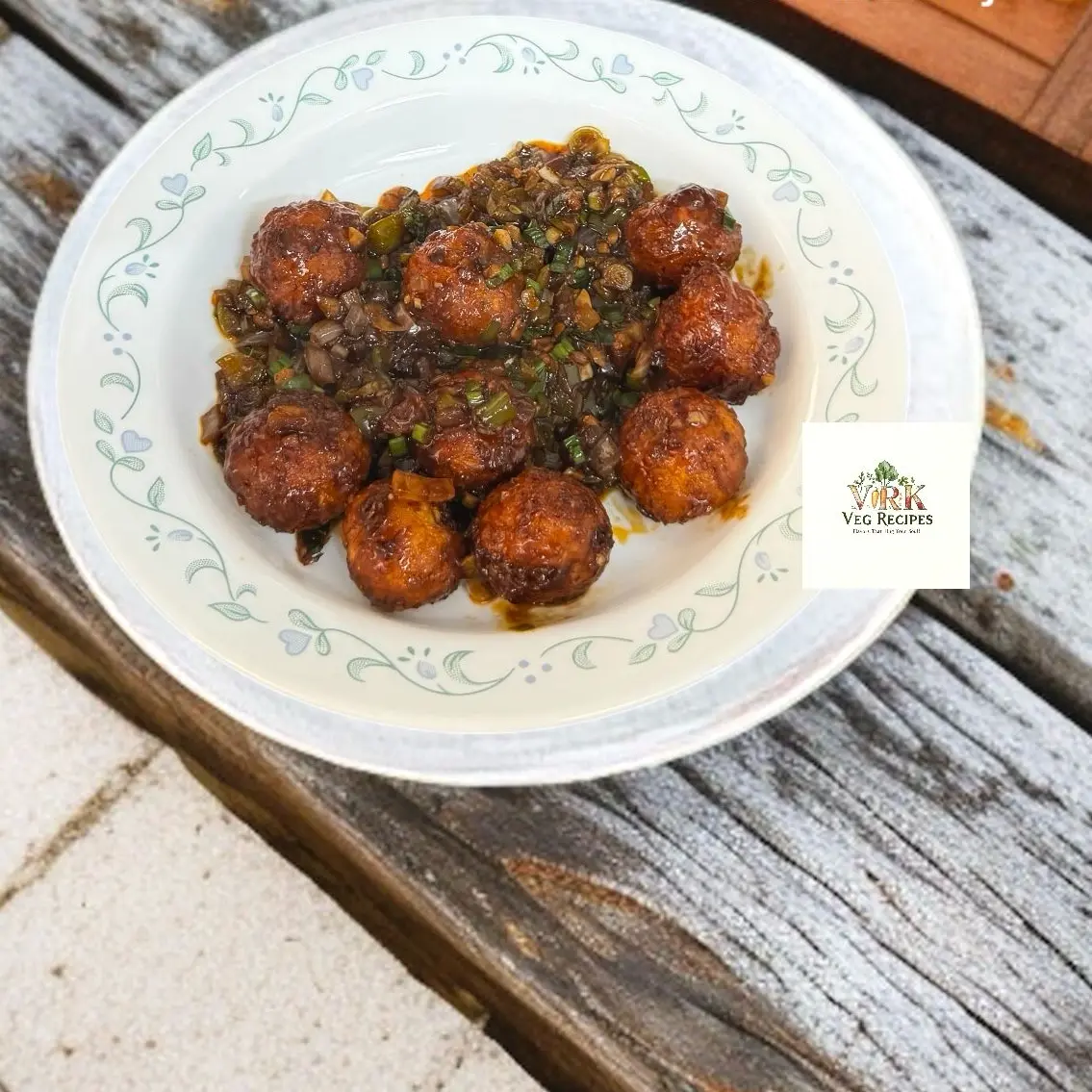 Veg Manchurian balls in spicy Schezwan gravy, garnished