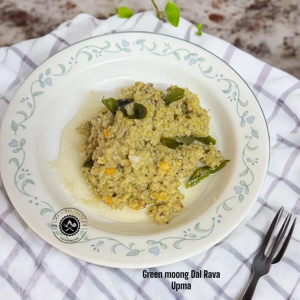 Green Moong Dal Rice Rava Upma | Wholesome South Indian A bowl of soft and fluffy green moong dal and rice rava upma, garnished with curry leaves and a dollop of ghee.