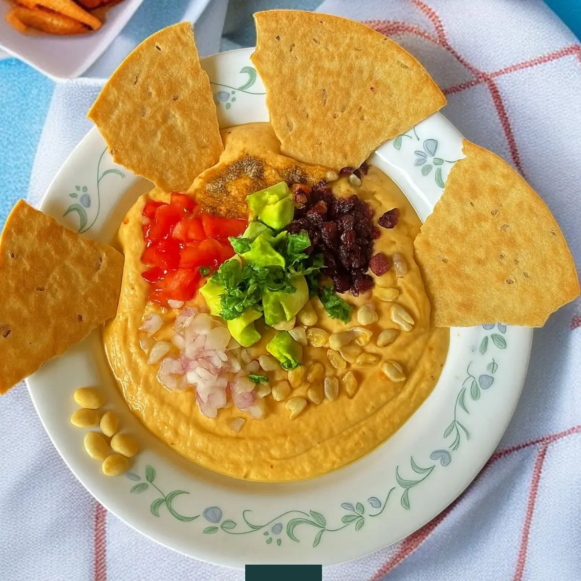 Creamy avocado chana yogurt dip topped with cranberries, peanuts, and veggies served with crispy khakra slices