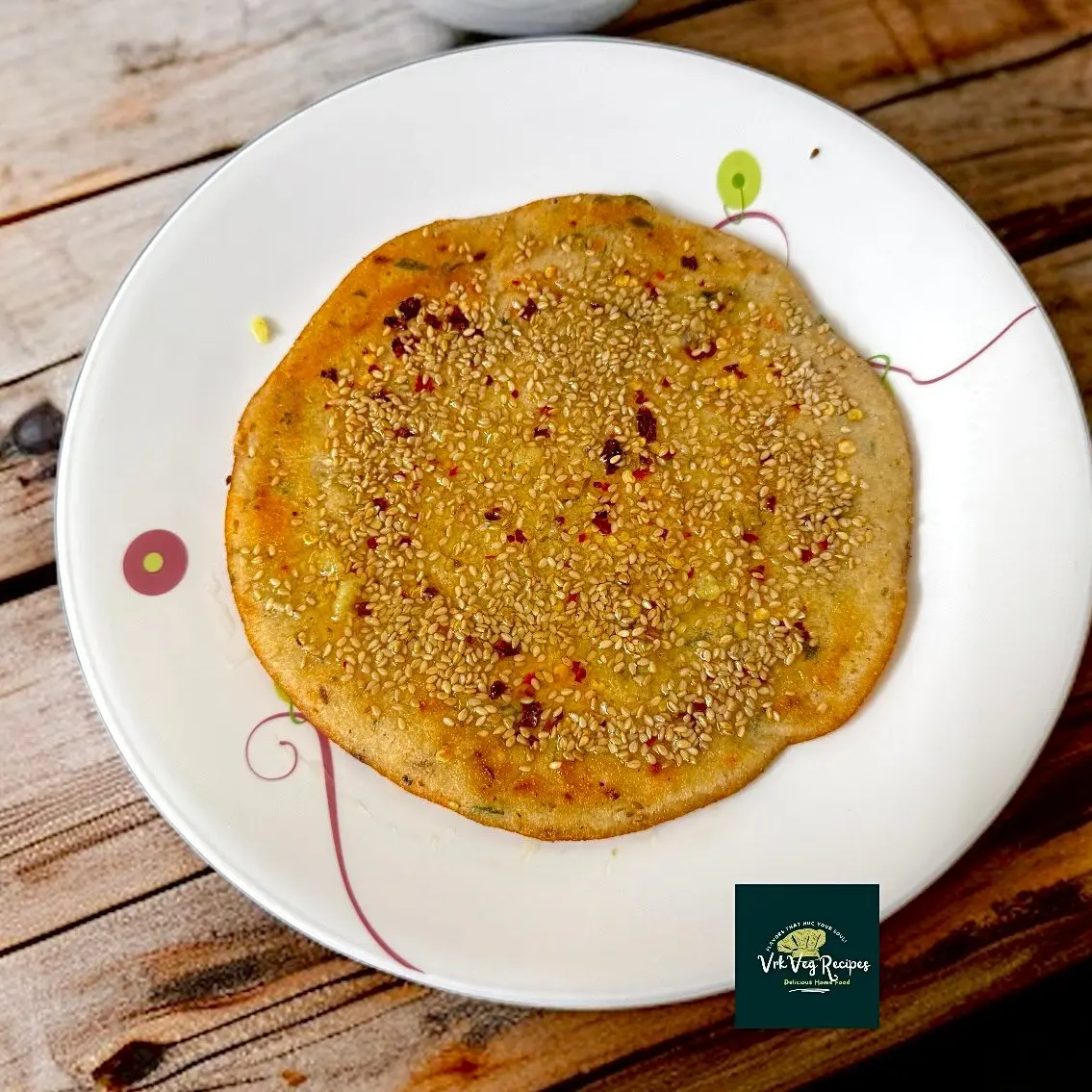 Crispy spicy jowar dosa topped with onions, sesame seeds, and red chilli flakes, roasted golden brown for a nutritious and flavorful meal.